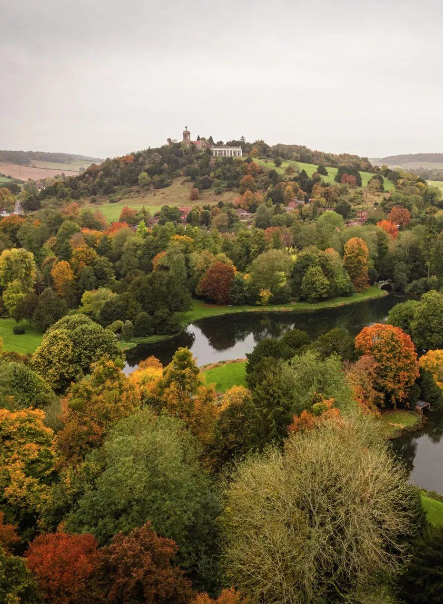 Autumn parkland with a lake and a hilltop church under grey cloud